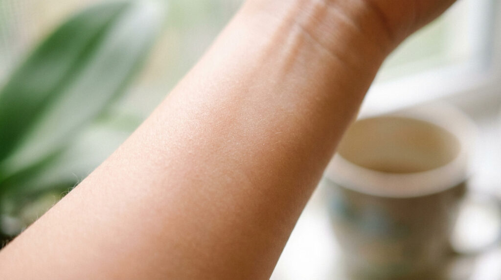 Gros plan sur l'avant-bras d'une personne, mettant en valeur la texture naturelle de la peau.