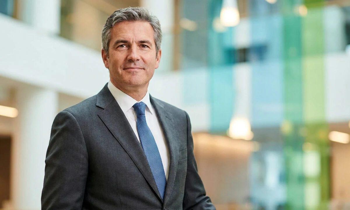 Portrait professionnel de Fabrice Camaioni en costume, souriant devant un arrière-plan de bureau moderne et lumineux.